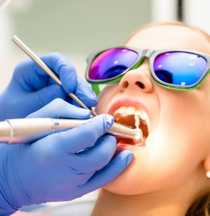 Close up of dentist polishing young girl’s teeth