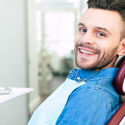 man sitting in dental chair and smiling