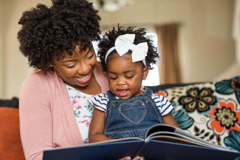 A woman reading a book to a little girl.