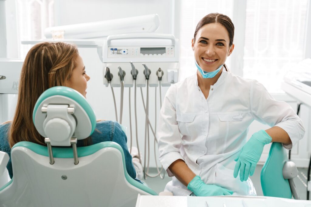 Dentist smiling next to patient in treatment room